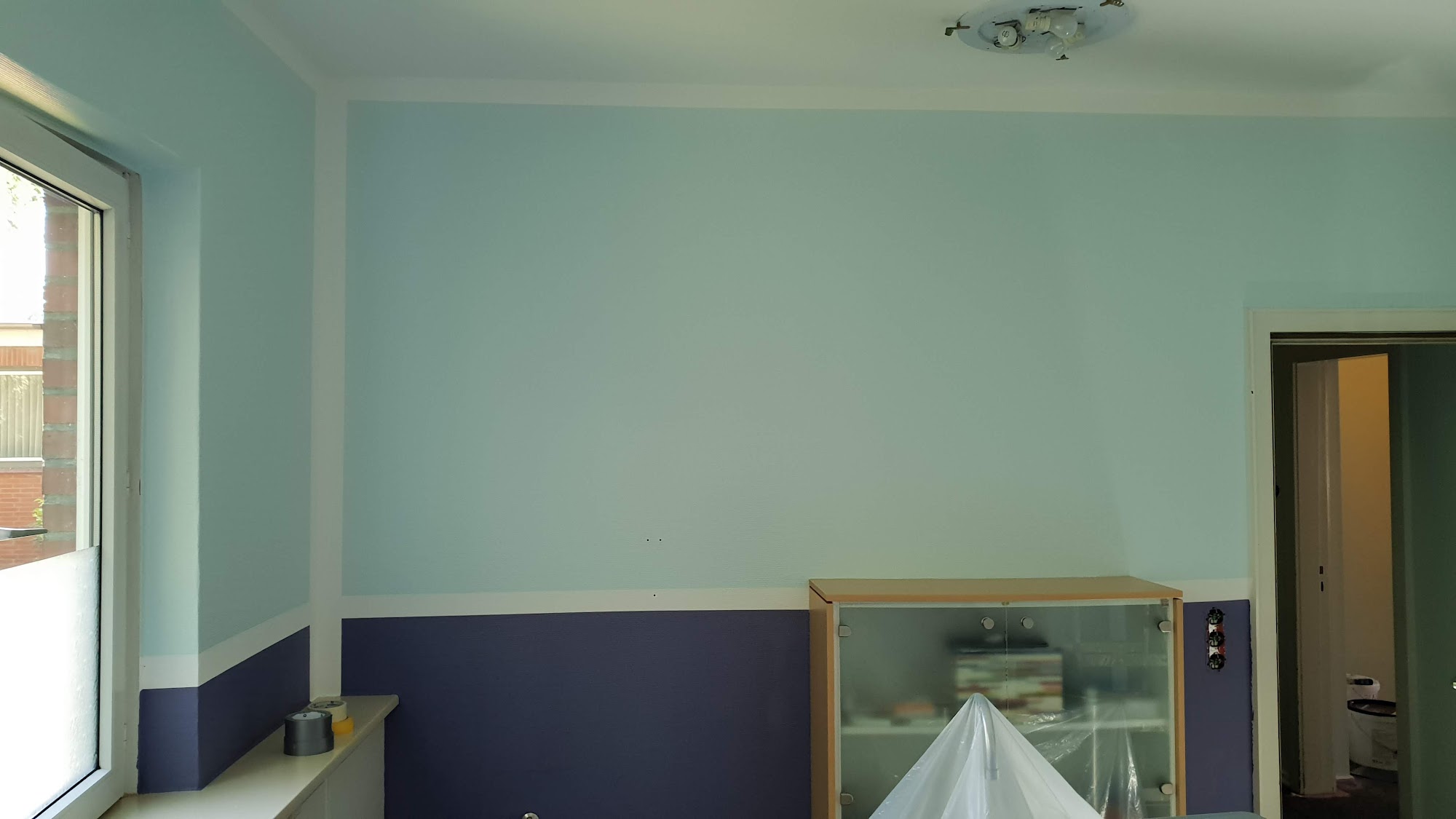 Zimmer mit zweifarbiger Wandgestaltung in Türkis und Violett