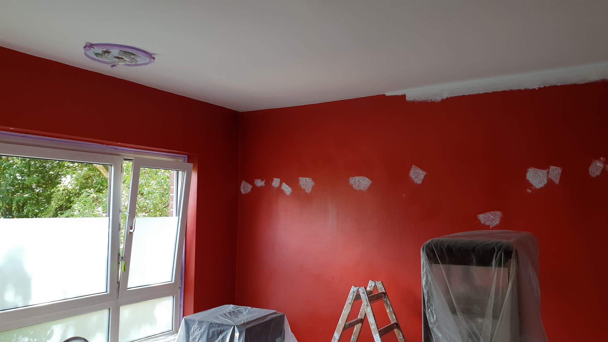 Raum mit roter Wand in Vorbereitung zum Streichen
